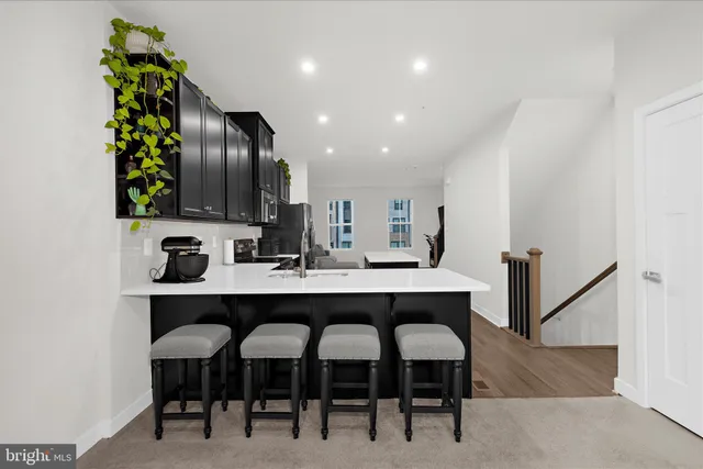 a kitchen with stainless steel appliances a dining table chairs sink and cabinets