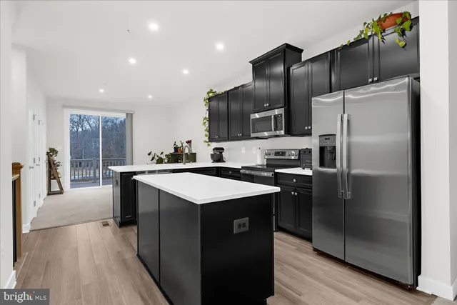 a kitchen with kitchen island stainless steel appliances a sink and refrigerator