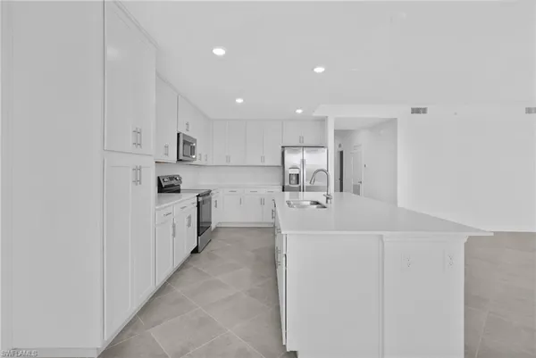 a kitchen that has a refrigerator a stove and white cabinets