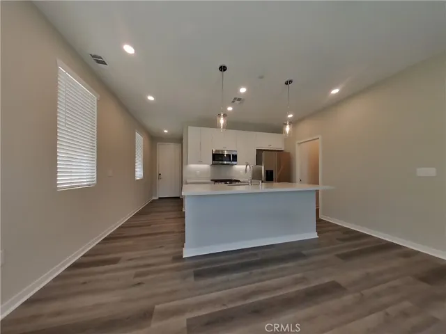 a view of kitchen with kitchen island stainless steel appliances wooden floor and window