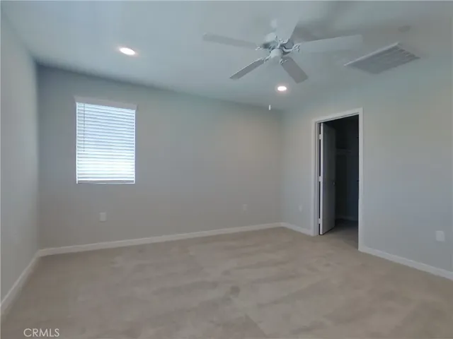 an empty room with ceiling fan and window