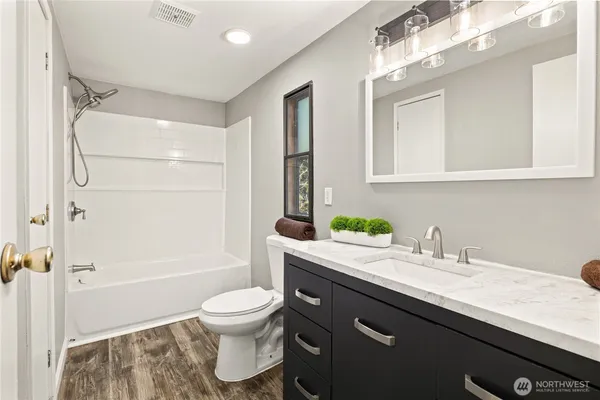 a bathroom with a granite countertop sink toilet a shower and a mirror