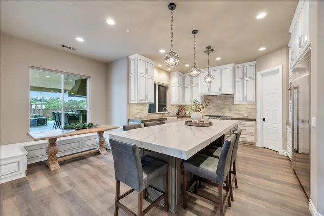 a dining room with wooden floor a chandelier a glass table and chairs