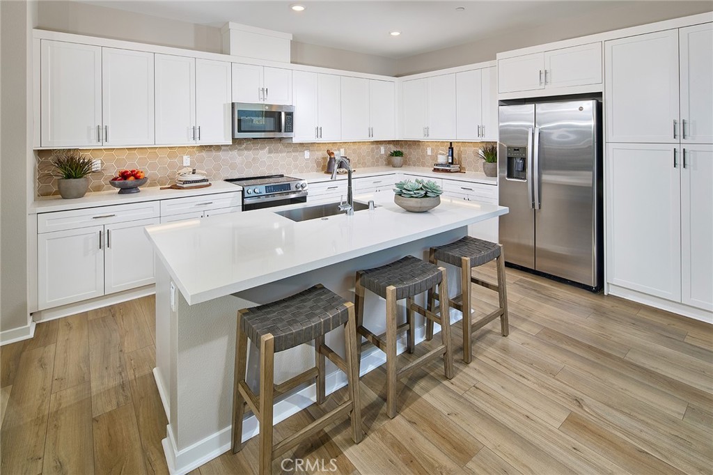 12706 Rosemount Road Eastvale, CA 92880 - Photo 5 of 25 a kitchen with stainless steel appliances granite countertop a refrigerator a stove a sink and white cabinets with wooden floor