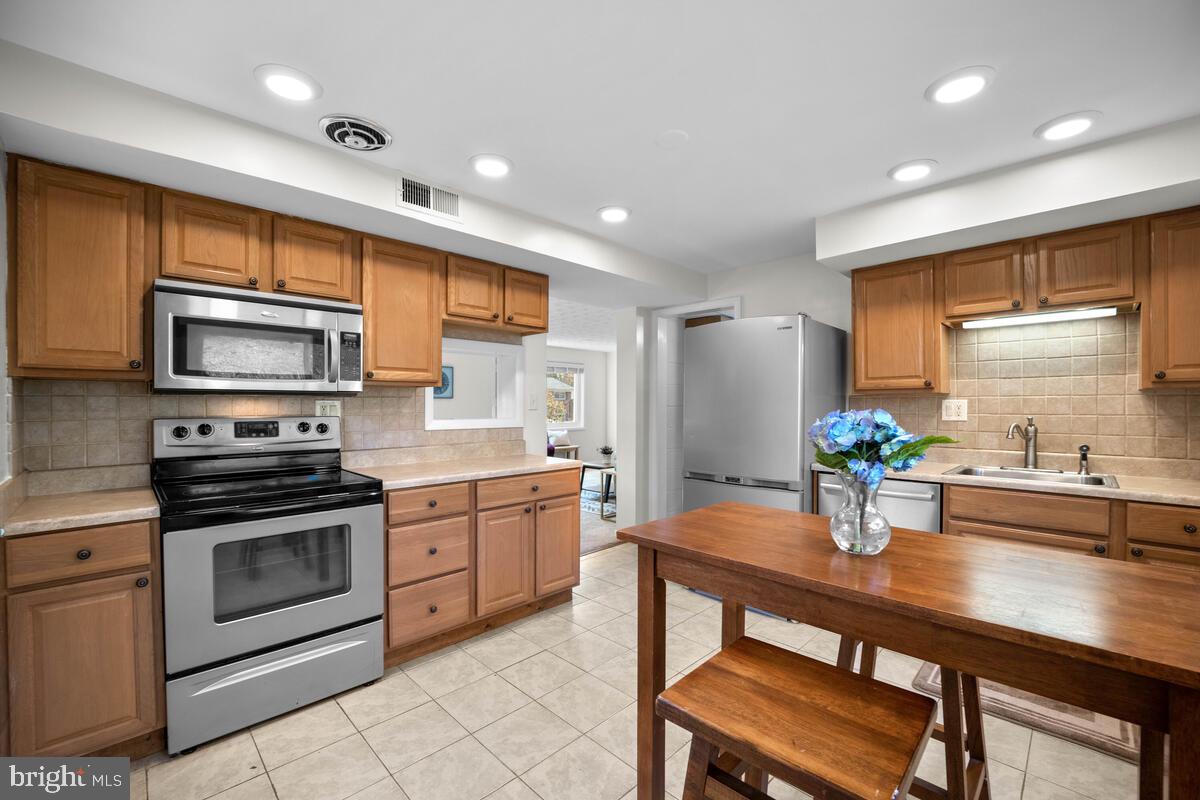 413 Waterford Road Silver Spring, MD 20901 - Photo 13 of 48 a kitchen with stainless steel appliances a dining table chairs stove refrigerator and cabinets