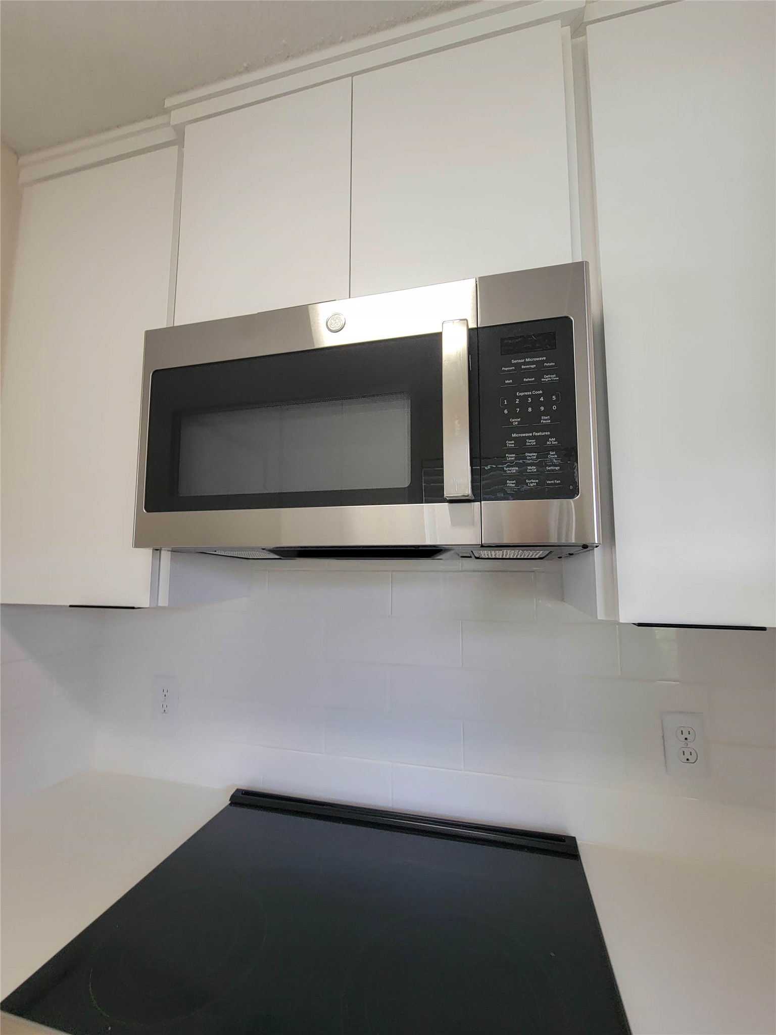 8706 Schick Road, Unit A Austin, TX 78729 - Photo 16 of 33 A sleek stainless steel microwave complements modern kitchen cabinetry and a glass cooktop.
