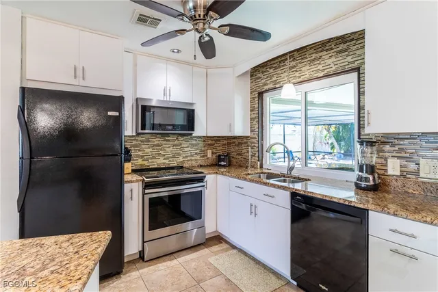 a kitchen with granite countertop stainless steel appliances a sink cabinets and a window