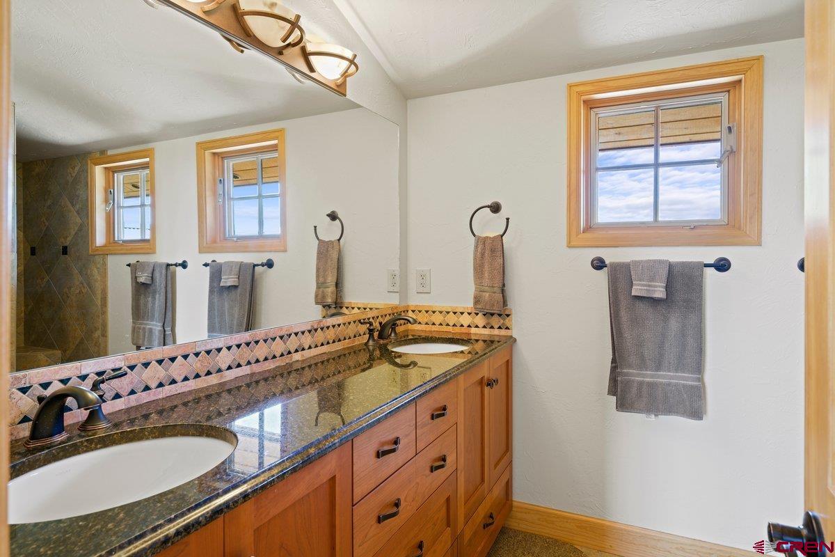 800 Pine Drive Ridgway, CO 81432 - Photo 21 of 35 a bathroom with a granite countertop double vanity sink and a mirror