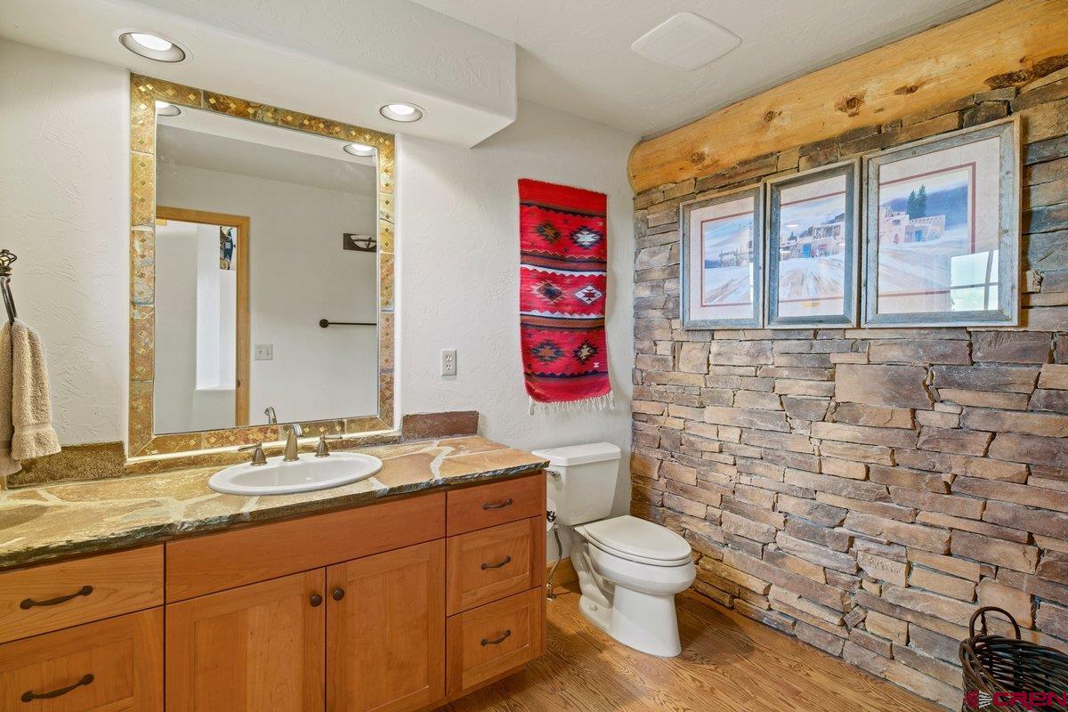 800 Pine Drive Ridgway, CO 81432 - Photo 27 of 35 a bathroom with a granite countertop toilet a sink and a large mirror