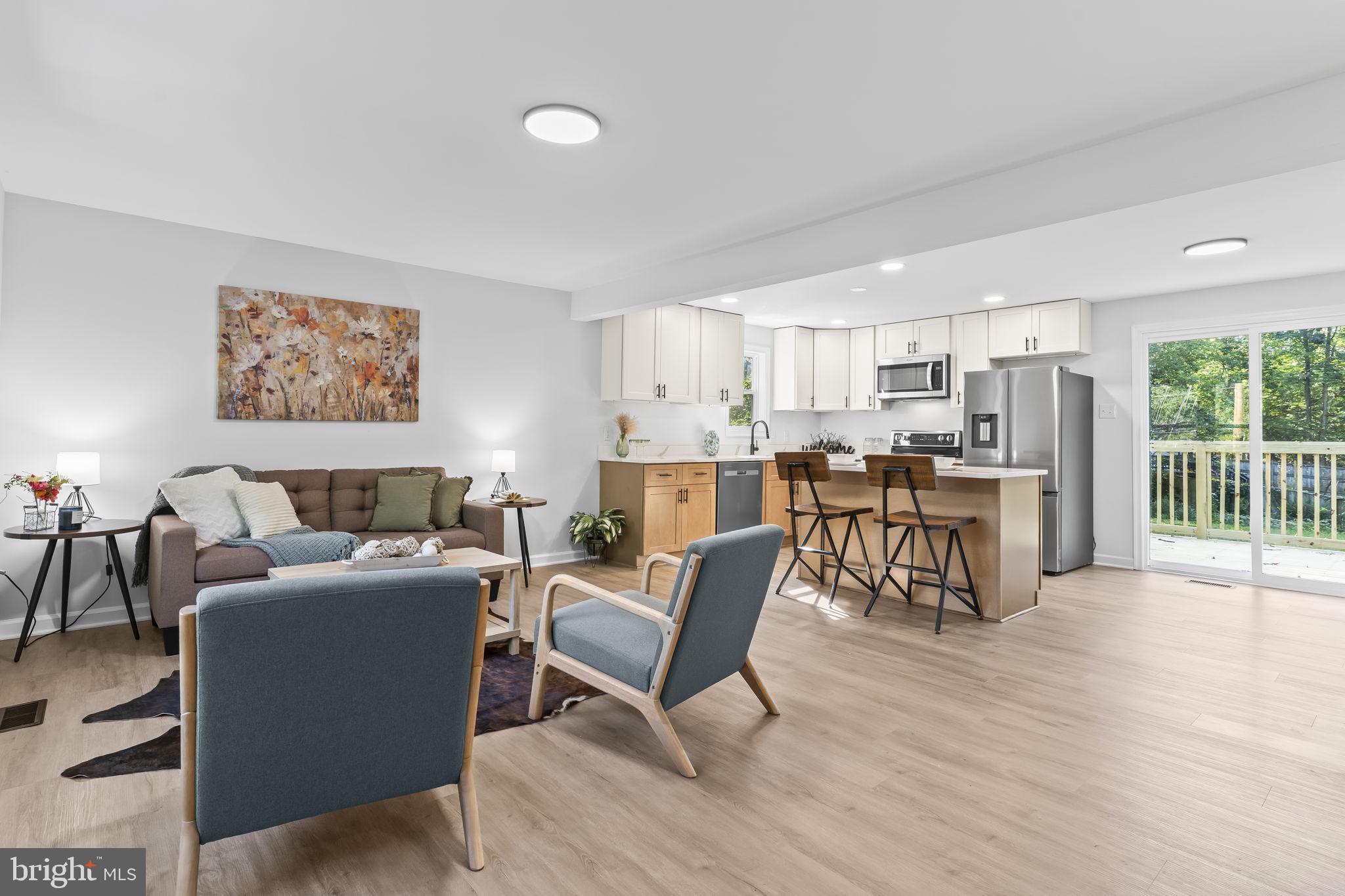 a living room with furniture and kitchen view with wooden floor