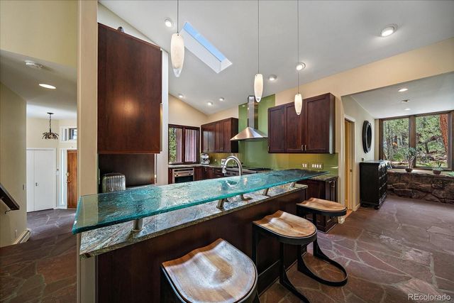 a room with stainless steel appliances kitchen island granite countertop a sink and chairs