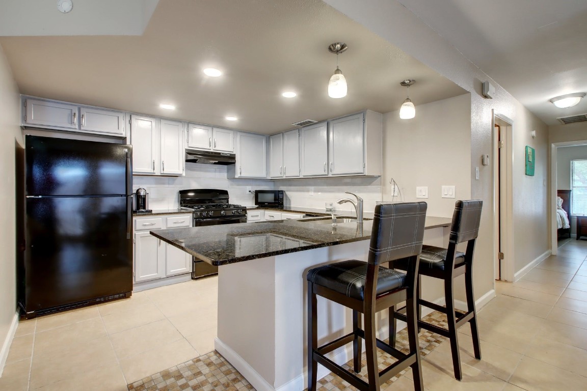 a kitchen with stainless steel appliances granite countertop a refrigerator a stove a sink a table and chairs
