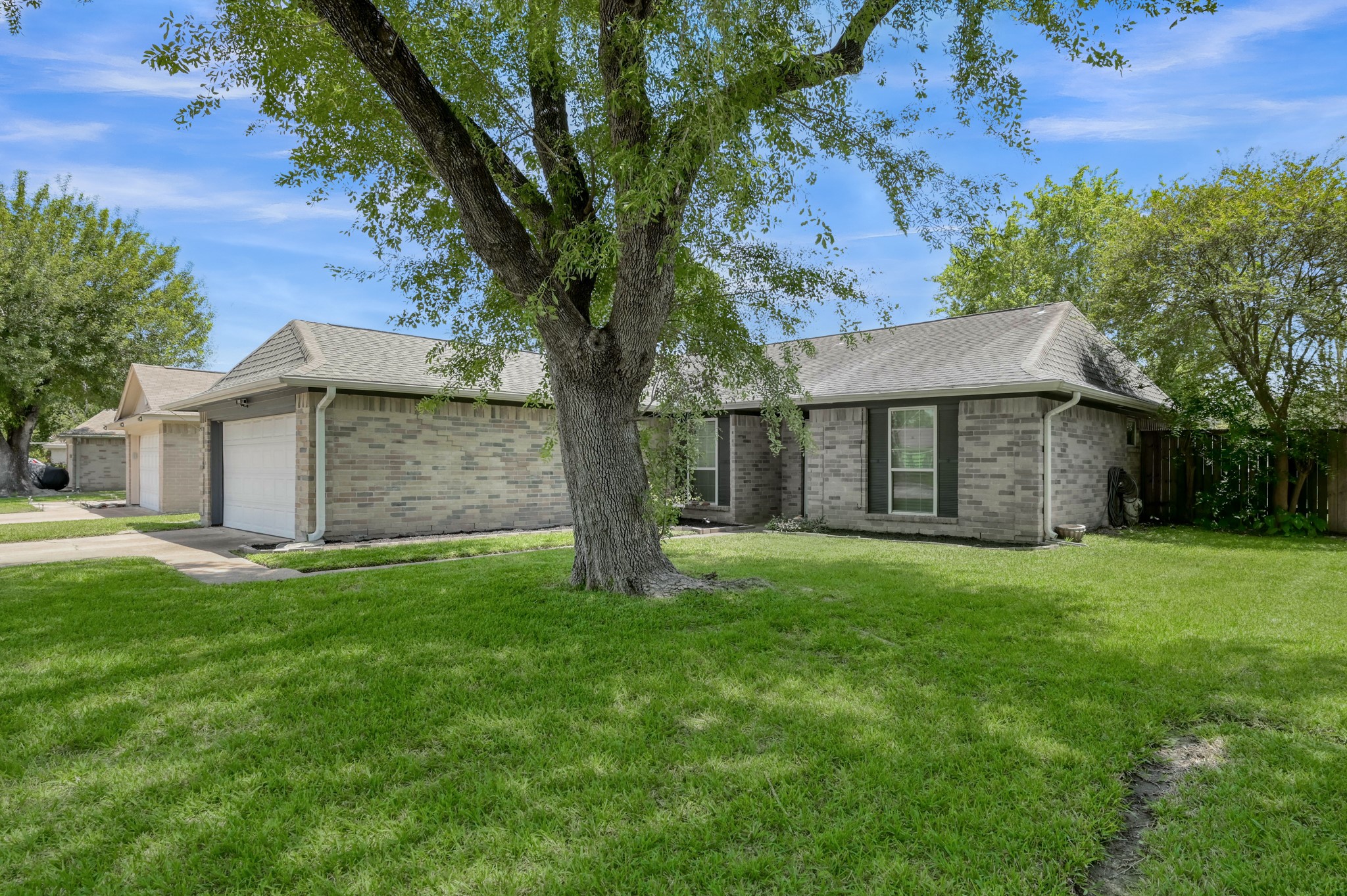 12015 Fallbrook Drive Houston, TX 77065 - Photo 2 of 29 Charming single-story brick home with a spacious front yard, mature tree, and attached two-car garage. Ideal for comfortable living in a serene neighborhood.