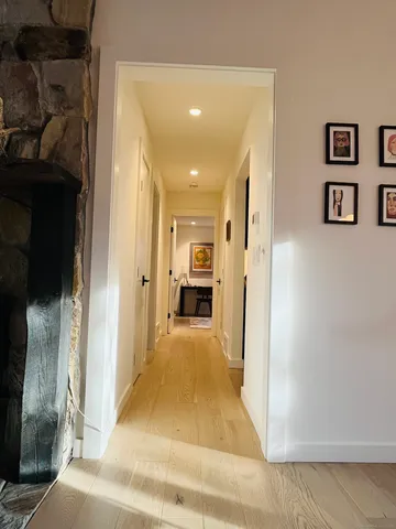 a view of a hallway with wooden floor and living room