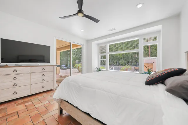 a bedroom with a large bed and a flat tv screen on dresser