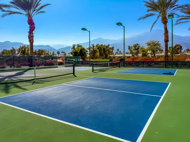 a view of a tennis ground with large trees