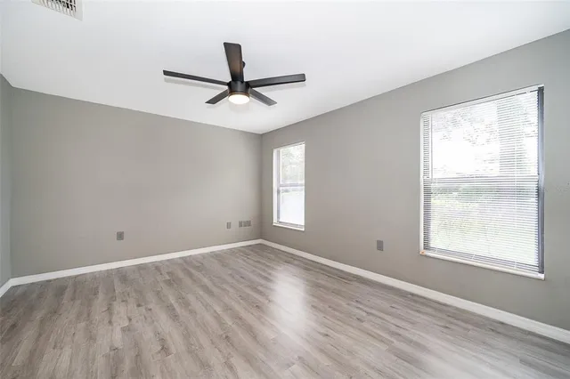 a view of empty room with wooden floor and fan