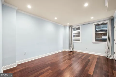 a view of an empty room with wooden floor and windows