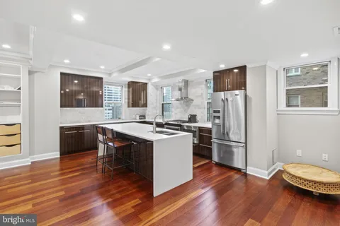 a kitchen with a refrigerator a microwave oven a sink dishwasher and white cabinets with wooden floor