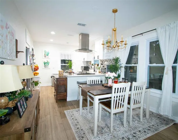 a dining room with wooden floor a chandelier a wooden table and chairs