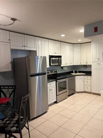 a kitchen with granite countertop a refrigerator sink and cabinets