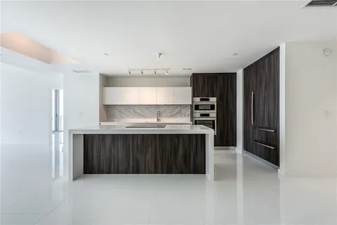 a kitchen with granite countertop a refrigerator and wooden cabinets