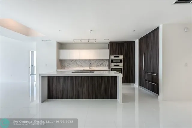 a view of kitchen with refrigerator and white cabinets