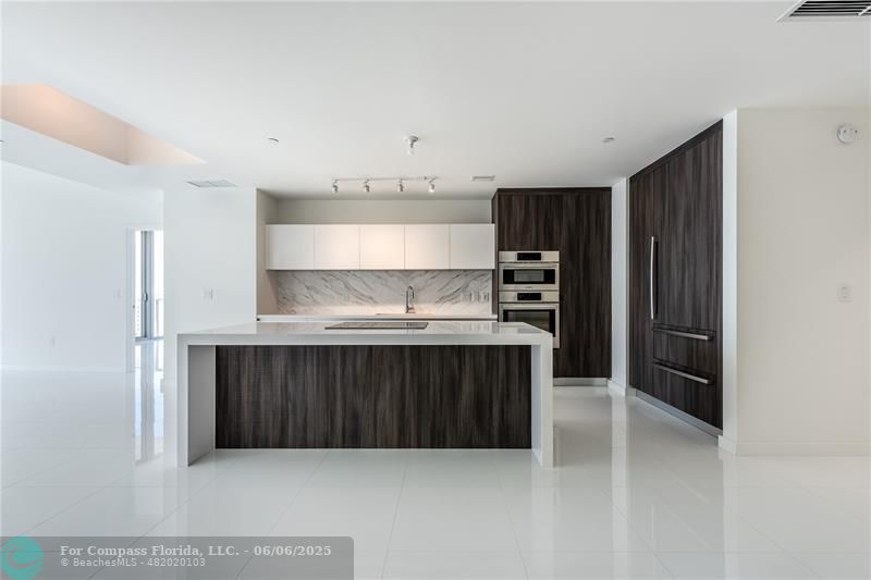 851 Northeast 1st Avenue, Unit 1912 Miami, FL 33132 - Photo 2 of 26 a kitchen with granite countertop a refrigerator and wooden cabinets
