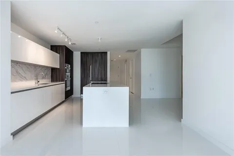 a view of kitchen with refrigerator and white cabinets