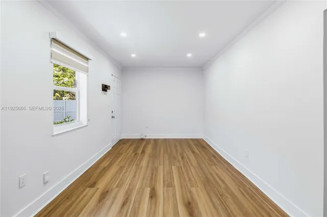a view of empty room with wooden floor and fan