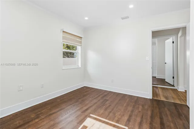 an empty room with wooden floor and a window