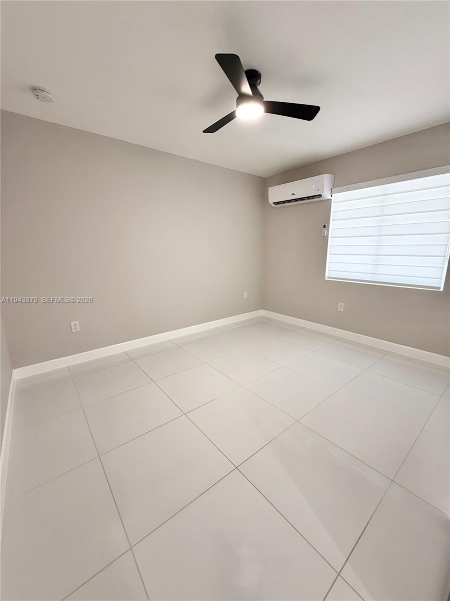 20530 Southwest 316th Street, Unit A Homestead, FL 33030 - Photo 4 of 7 an empty room with windows and ceiling fan
