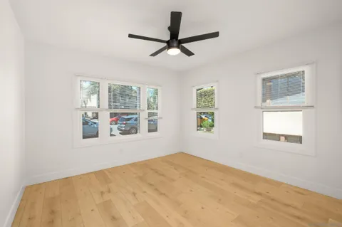 a view of empty room with wooden floor and ceiling fan
