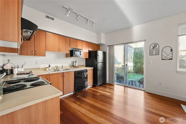 a kitchen with a refrigerator a stove a sink dishwasher and wooden cabinets with wooden floor