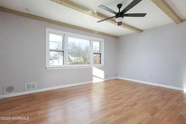 an empty room with wooden floor fan and windows