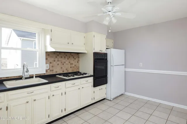 a kitchen with granite countertop white cabinets white stainless steel appliances and a sink