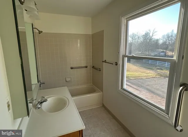 a bathroom with a tub a sink a window and a shower