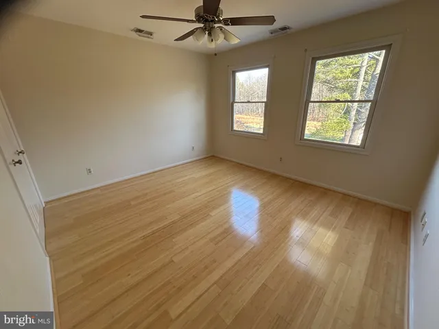 a view of an empty room with a window and wooden floor