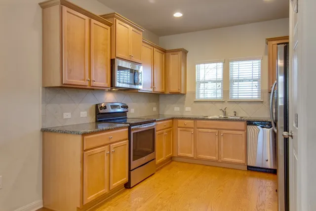 a kitchen with stainless steel appliances granite countertop a stove a sink and a microwave