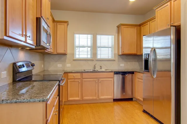 a kitchen with stainless steel appliances granite countertop a sink refrigerator stove and microwave