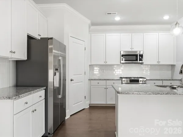 a kitchen with stainless steel appliances granite countertop a refrigerator stove and white cabinets