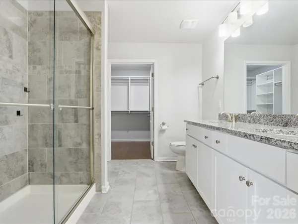 a spacious bathroom with a granite countertop sink a mirror and a shower