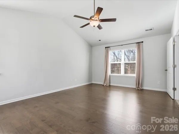 an empty room with wooden floor ceiling fan and windows