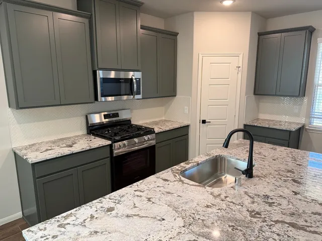 a kitchen with granite countertop a stove and a sink
