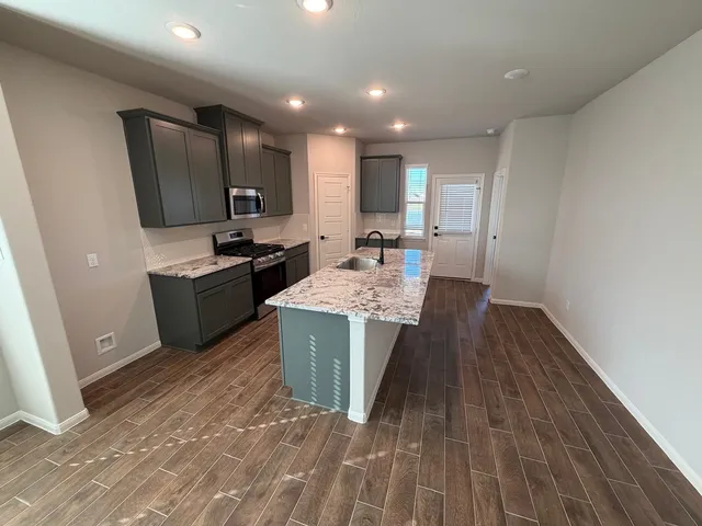 a large kitchen with stainless steel appliances a large counter top a sink a stove a refrigerator and cabinets