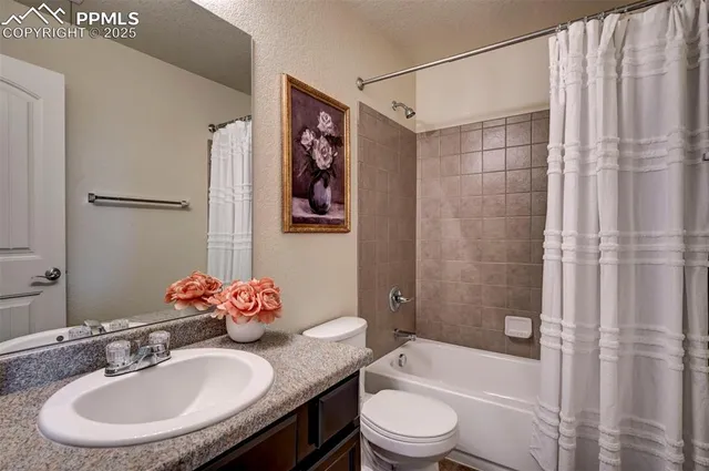 a bathroom with a granite countertop sink a toilet a mirror a vanity and shower