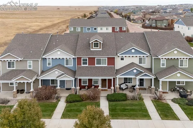 a aerial view of a brick house next to a yard with big trees