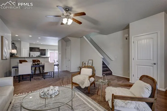 a living room with furniture kitchen view and a wooden floor