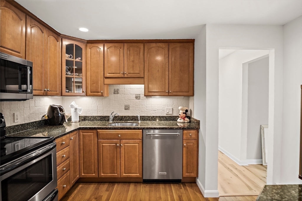 386 Great Road, Unit A8 Acton, MA 01720 - Photo 11 of 26 a kitchen with stainless steel appliances granite countertop a stove a sink and a microwave