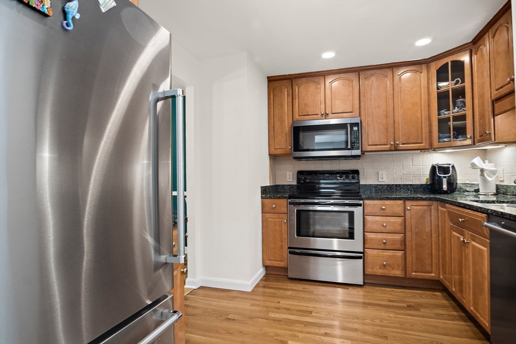 386 Great Road, Unit A8 Acton, MA 01720 - Photo 10 of 26 a kitchen with granite countertop a refrigerator stove and microwave